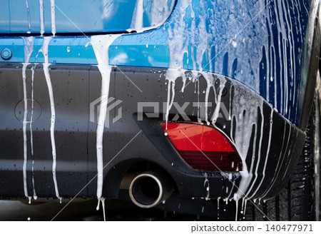 Blue car wash with white soap foam and professional auto care service. Car cleaning service concept. Vehicle cleaning service. Foam wash car detailing. Blue luxury SUV car is covered with white foam. Blue car wash with white soap foam and professional auto care service. Car cleaning service concept. Vehicle cleaning service. Foam wash car detailing. Blue luxury SUV car is covered with white foam. 140477971
