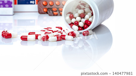 Red and white capsules pill spilled out from white plastic bottle. Prescription drug. Healthcare and medicine. Antibiotics drug. Antimicrobial capsule pills. Pharmaceutical industry. Pharmacy product. Red and white capsules pill spilled out from white plastic bottle. Prescription drug. Healthcare and medicine. Antibiotics drug. Antimicrobial capsule pills. Pharmaceutical industry. Pharmacy product. 140477981