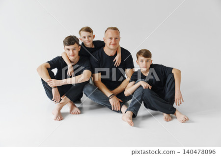 Family members sit together in a simple indoor space Family members sit together in a simple indoor space 140478096