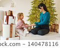 Woman and girl share moments by decorated Christmas tree 140478116