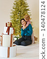 Woman and child enjoy time together by a Christmas tree 140478124