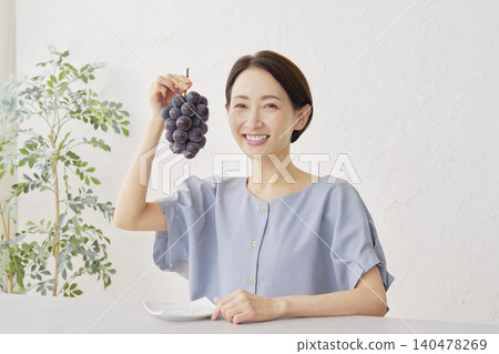 一位女士在客廳吃巨峰葡萄 140478269