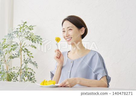 A woman eating persimmon in the living room A woman eating persimmon in the living room 140478271