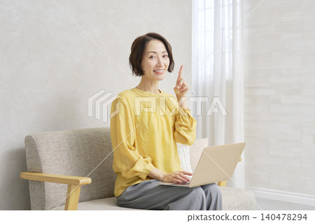 Woman using a computer in the living room pointing Woman using a computer in the living room pointing 140478294