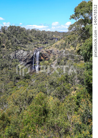 Scenic view of Ebor Falls and surrounding natural landscape in New South Wales, Australia. Waterfall cascading over rock formation within forest environment of Guy Fawkes River National Park. Scenic view of Ebor Falls and surrounding natural landscape in New South Wales, Australia. Waterfall cascading over rock formation within forest environment of Guy Fawkes River National Park. 140478512