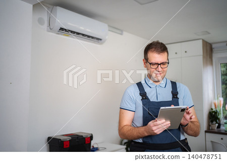 Technician checking air conditioner with digital tablet Technician checking air conditioner with digital tablet 140478751