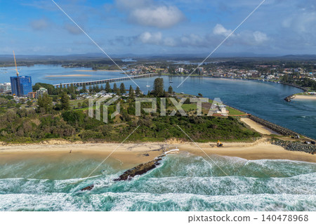 Aerial view of Forster Main Beach featuring a stranded sailboat resting on the sand with the Forster and Tuncurry Bridge spanning Wallis Lake in the background. Aerial view of Forster Main Beach featuring a stranded sailboat resting on the sand with the Forster and Tuncurry Bridge spanning Wallis Lake in the background. 140478968