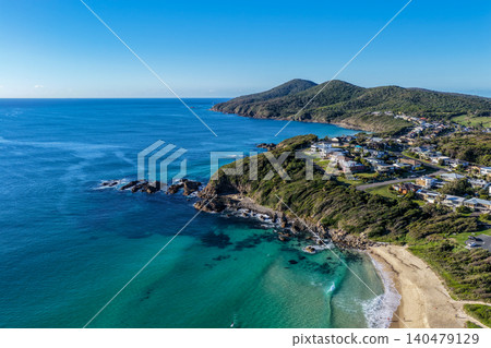 Aerial scene capturing One Mile Beach near Forster, NSW, Australia, with a rugged rocky headland in the foreground and Cape Hawke visible in the background. Aerial scene capturing One Mile Beach near Forster, NSW, Australia, with a rugged rocky headland in the foreground and Cape Hawke visible in the background. 140479129