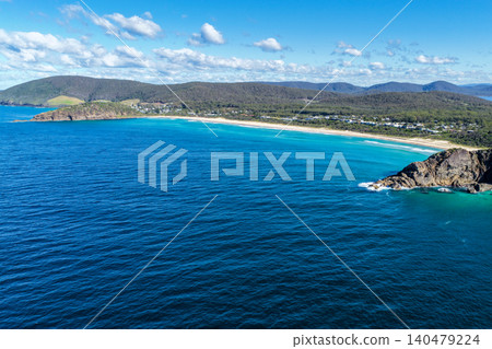 Aerial scene capturing Boomerang Beach near Pacific Palms, NSW, Australia, nestled between rugged rocky headlands. The sweeping sandy shoreline, clear ocean waters and dramatic coastal landscape Aerial scene capturing Boomerang Beach near Pacific Palms, NSW, Australia, nestled between rugged rocky headlands. The sweeping sandy shoreline, clear ocean waters and dramatic coastal landscape 140479224