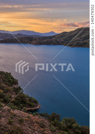 Vertical Aerial view of Glenbawn Dam at sunset in NSW Australia. Drone photograph captures calm dam waters, surrounding hills and colourful evening sky reflections from above. Vertical Aerial view of Glenbawn Dam at sunset in NSW Australia. Drone photograph captures calm dam waters, surrounding hills and colourful evening sky reflections from above. 140479302