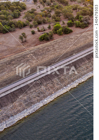 Vertical Aerial close up view of the Glenbawn Dam wall and surrounding landscape in NSW Australia. Drone photograph captures the engineering structure, reservoir waters and rugged mountain scenery Vertical Aerial close up view of the Glenbawn Dam wall and surrounding landscape in NSW Australia. Drone photograph captures the engineering structure, reservoir waters and rugged mountain scenery 140479303