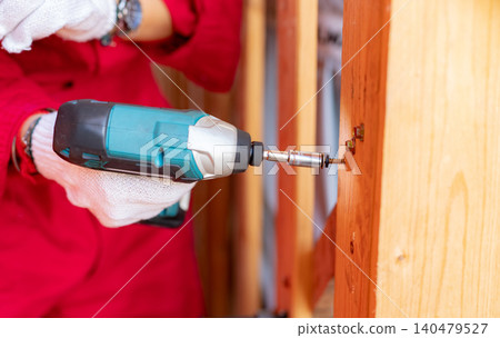 Carpenter and screwdriver hand tool. A skilled worker set to work drilling and installing wooden fixtures, using electric screwdriver to construct and repair parts of house with precision and care. Carpenter and screwdriver hand tool. A skilled worker set to work drilling and installing wooden fixtures, using electric screwdriver to construct and repair parts of house with precision and care. 140479527