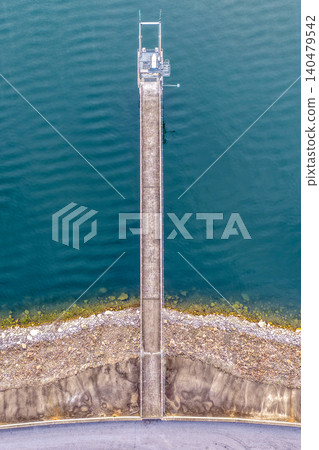 Vertical Aerial downward view of the Glenbawn Dam wall with the walkway leading out to the water intake in NSW Australia. Drone photograph captures the engineering infrastructure, reservoir waters Vertical Aerial downward view of the Glenbawn Dam wall with the walkway leading out to the water intake in NSW Australia. Drone photograph captures the engineering infrastructure, reservoir waters 140479542