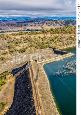 Vertical Aerial view of Glenbawn Dam and the spillway with surrounding landscape in NSW Australia. Drone photograph captures the engineering infrastructure, expansive reservoir and rugged inland Vertical Aerial view of Glenbawn Dam and the spillway with surrounding landscape in NSW Australia. Drone photograph captures the engineering infrastructure, expansive reservoir and rugged inland 140479617