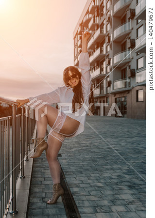 Woman stockings city young playful female posing in white shirt and lingerie on a modern urban walkway during sunset Woman stockings city young playful female posing in white shirt and lingerie on a modern urban walkway during sunset 140479672