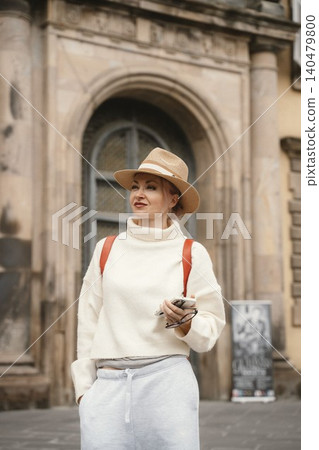 Woman in Hat Smiling While Holding Phone Outdoors Woman in Hat Smiling While Holding Phone Outdoors 140479800