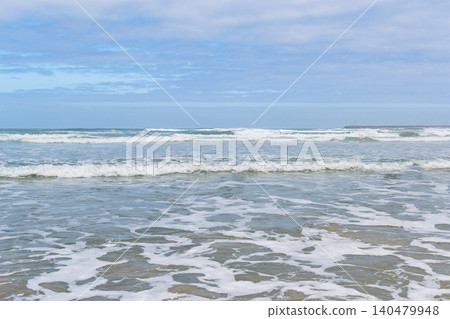 Serene ocean waves crashing gently on a sandy beach under a soft cloudy sky, evoking a peaceful sense of tranquility and freedom. Perfect for travel or wellness designs. Nobody. Serene ocean waves crashing gently on a sandy beach under a soft cloudy sky, evoking a peaceful sense of tranquility and freedom. Perfect for travel or wellness designs. Nobody. 140479948