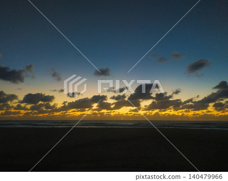A breathtaking coastal sunset with dramatic dark clouds over the ocean horizon. This scenic view offers a sense of tranquility, perfect for travel themes and atmospheric backgrounds. A breathtaking coastal sunset with dramatic dark clouds over the ocean horizon. This scenic view offers a sense of tranquility, perfect for travel themes and atmospheric backgrounds. 140479966