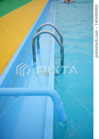 A photographic image of a railing installed in an outdoor swimming pool during the summer, with the water's surface clear. A photographic image of a railing installed in an outdoor swimming pool during the summer, with the water's surface clear. 140480068