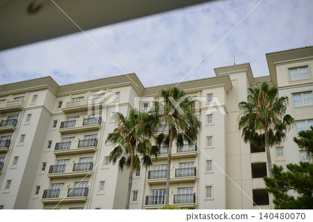 A stock photo of the exterior of a tropical resort hotel lined with palm trees. A stock photo of the exterior of a tropical resort hotel lined with palm trees. 140480070