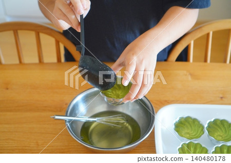 Photo of a child pouring homemade jelly into a mold. Photo of a child pouring homemade jelly into a mold. 140480178