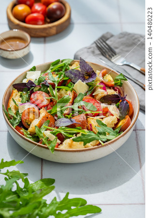 Tuscan panzanella salad with tomatoes, red onion, arugula, basil, cheese and bread in a bowl Tuscan panzanella salad with tomatoes, red onion, arugula, basil, cheese and bread in a bowl 140480223