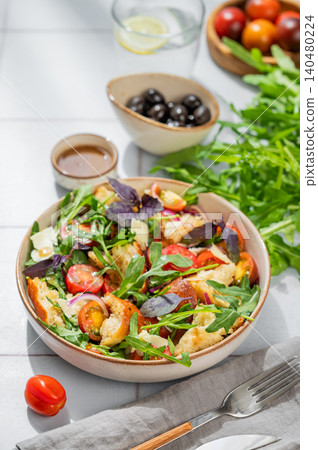 Tuscan panzanella salad with tomatoes, red onion, arugula, basil, cheese and bread in a bowl Tuscan panzanella salad with tomatoes, red onion, arugula, basil, cheese and bread in a bowl 140480224