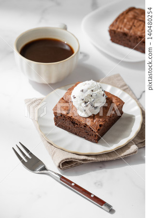 A pieces of chocolate brownie with ice cream on a plate and a cup of espresso coffee A pieces of chocolate brownie with ice cream on a plate and a cup of espresso coffee 140480254