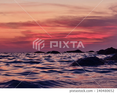 Vibrant sunset over rocky coastal waves, pink and coral sky reflecting on rippling ocean surface. Vibrant sunset over rocky coastal waves, pink and coral sky reflecting on rippling ocean surface. 140480652
