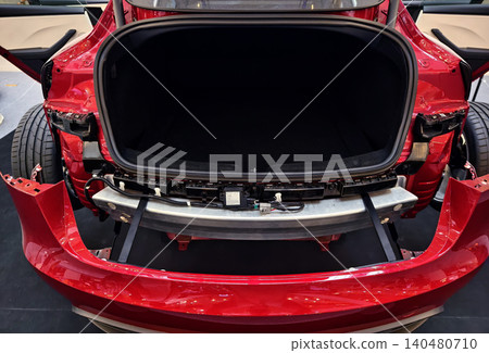Red car rear bumper open trunk reveals exposed crash beam, mounting brackets, sensors, inner chassis. Red car rear bumper open trunk reveals exposed crash beam, mounting brackets, sensors, inner chassis. 140480710