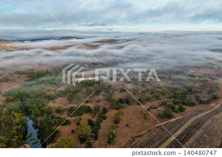 Vertical Aerial image of the scenic landscape alongside Glenbawn Dam with fog rolling through the valley in NSW Australia. Drone photograph captures rugged mountain scenery, atmospheric low cloud 140480747