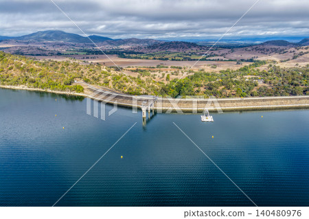 Vertical Aerial view of Glenbawn Dam and the dam wall leading towards the surrounding mountains in NSW Australia. Drone photograph captures the expansive reservoir, rugged inland landscape Vertical Aerial view of Glenbawn Dam and the dam wall leading towards the surrounding mountains in NSW Australia. Drone photograph captures the expansive reservoir, rugged inland landscape 140480976