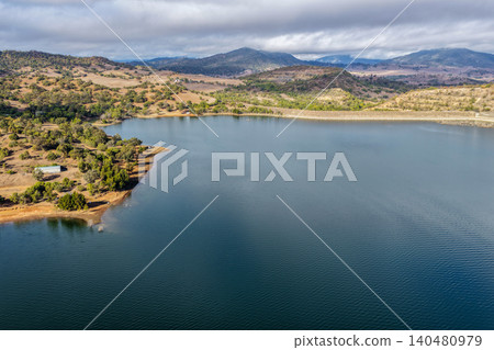 Vertical Aerial view of Glenbawn Dam and the dam wall leading towards the surrounding mountains in NSW Australia. Drone photograph captures the expansive reservoir, rugged inland landscape Vertical Aerial view of Glenbawn Dam and the dam wall leading towards the surrounding mountains in NSW Australia. Drone photograph captures the expansive reservoir, rugged inland landscape 140480979