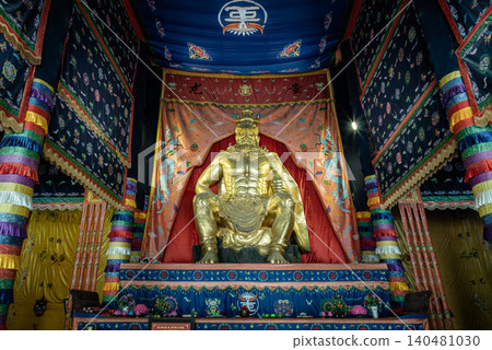majestic, muscular golden deity sits enthroned beneath an ornate canopy, surrounded by richly detailed, multicolored tapestries and traditional embroidered banners that evoke a profound sense of 140481030