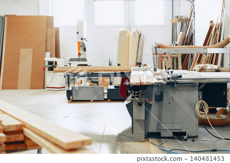 Woodworking takes place in a busy furniture workshop with various tools and materials around Woodworking takes place in a busy furniture workshop with various tools and materials around 140481453