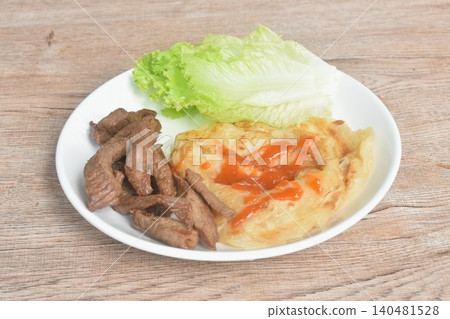 fried roti southern flat bread dressing chili sauce crispy with salty fermenting beef fat meat and cos lettuce vegetable salad on plate 140481528