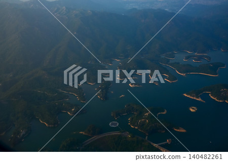 Looking from the airplane window with Hong Kong cityscape. The view of Hong Kong city, Hong Kong landscape from the above. Landscape, travel concept and nature scene. Looking from the airplane window with Hong Kong cityscape. The view of Hong Kong city, Hong Kong landscape from the above. Landscape, travel concept and nature scene. 140482261
