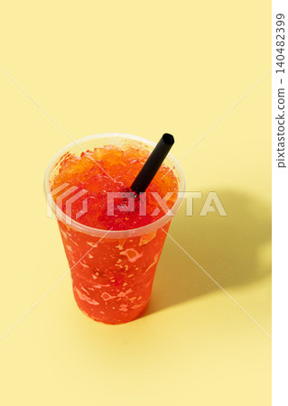 Red fruit slushie drink in plastic cup on yellow background 140482399