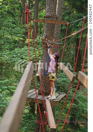 The girl moves the carbine along the rope for safe passage of obstacles along the route at altitude 140482447