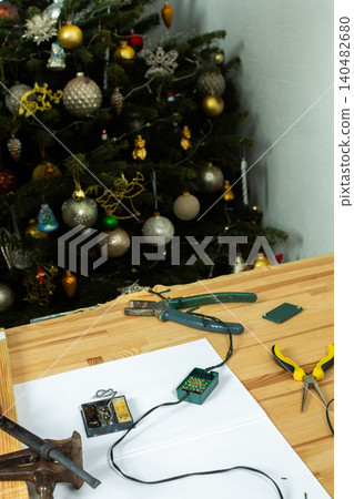 Fixing the wires of a Christmas tree garland. Tools like pliers and scissors are on the table. Electrical parts are laid out for repair Fixing the wires of a Christmas tree garland. Tools like pliers and scissors are on the table. Electrical parts are laid out for repair 140482680