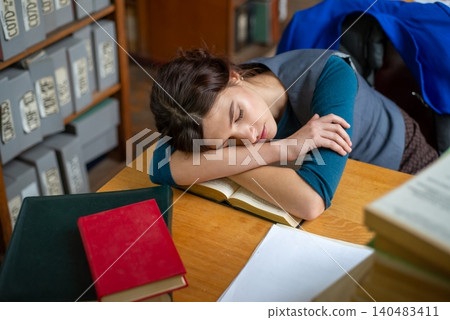 Tired female student fell asleep while reading a book. Tired female student fell asleep while reading a book. 140483411