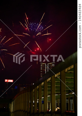 Stunning and colorful fireworks display in the night sky with Hong Kong city background. Watching the fireworks from the bridge. Real fireworks background. For celebration. Stunning and colorful fireworks display in the night sky with Hong Kong city background. Watching the fireworks from the bridge. Real fireworks background. For celebration. 140483484