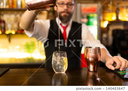 Bearded bartender is making alcohol cocktail at counter 140483647