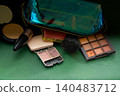 Makeup Collection with Iridescent Bag, Eyeshadow Palette, and Beauty Products Cosmetic on Green background 140483712