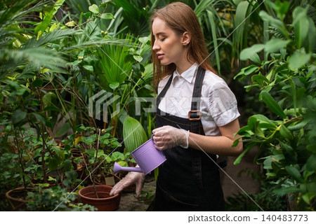 Florist with watering can in greenhouse Florist with watering can in greenhouse 140483773