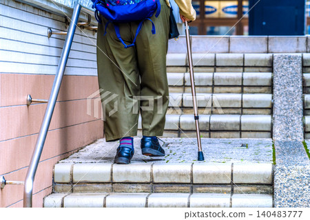 Ankle view of Yokohama, Japan... An elderly woman (wearing a mask) using a cane to climb stairs. Loose, flexible shoes... 140483777