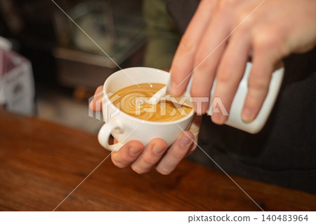 A close up of a barista pouring milk to create latte art A close up of a barista pouring milk to create latte art 140483964