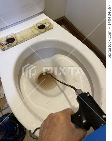 場景展示了將金屬絲工具插入馬桶,以修復和清除堵塞物的過程。 場景展示了將金屬絲工具插入馬桶,以修復和清除堵塞物的過程。 140484067