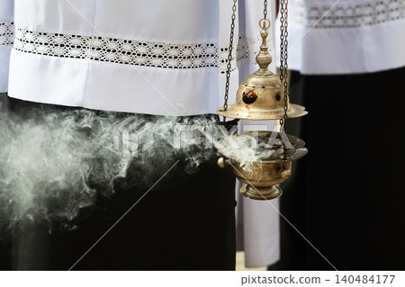 Thurible censer emitting incense smoke during religious ritual Thurible censer emitting incense smoke during religious ritual 140484177