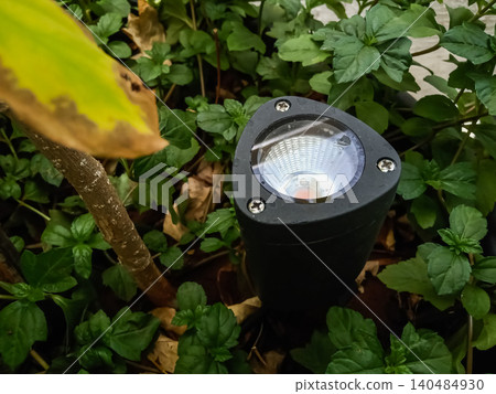 Modern Black LED Garden Spike Spotlight for Landscape Lighting adjustable black LED spike light installed in garden soil near a tree. 140484930